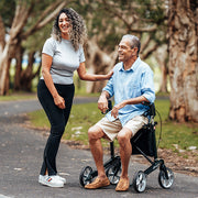 Two people outdoors enjoying the park with one person in seated in a walker